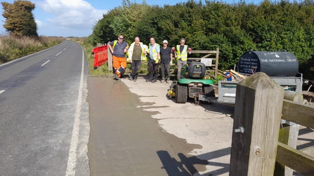 Image of a group of people standing by a gate and admiring the repair they have made to the joint at the junction of the site road and Upper Road